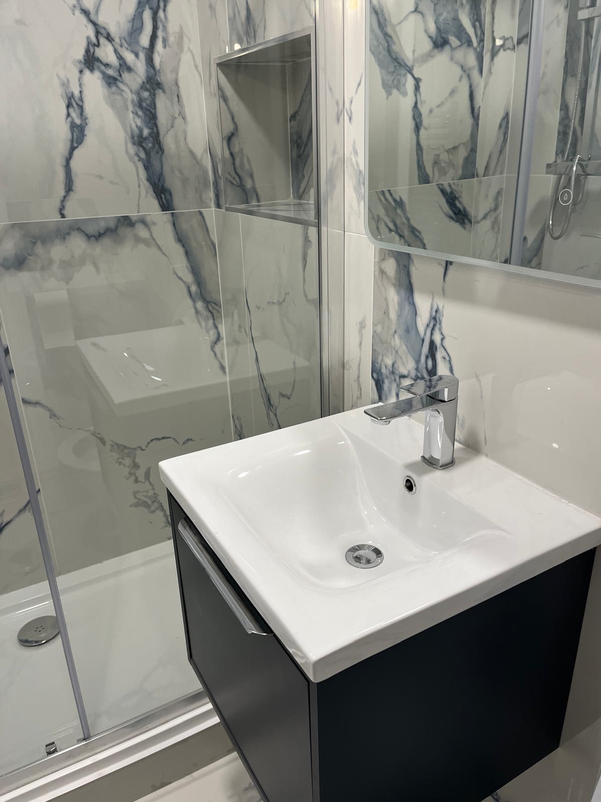 Bathroom after: marble-effect tiled shower with a navy wall-hung vanity unit