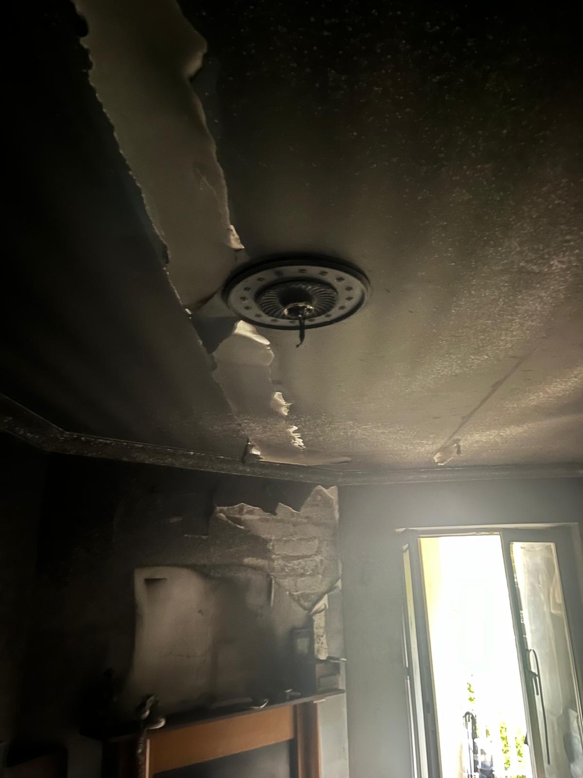 Living area after the fire: blackened ceiling with torn plaster and smoke-stained walls