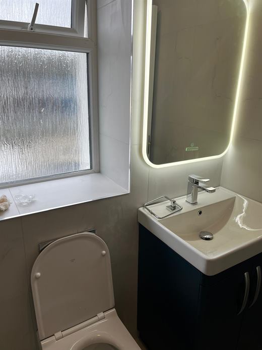 Basin, wall-hung toilet and backlit mirror
