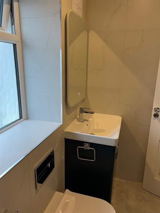 Bathroom vanity beside a window with marble-effect tiles