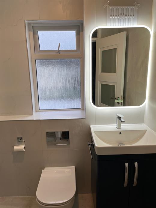 Bathroom with backlit mirror and navy vanity unit