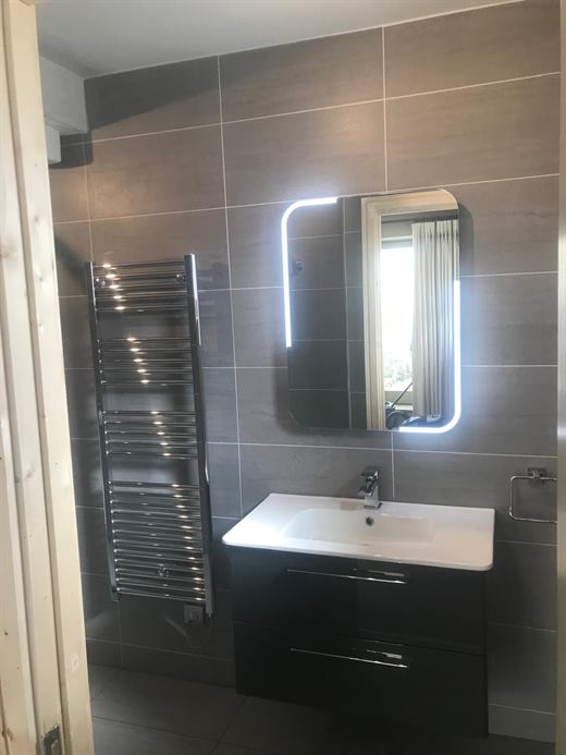 Bathroom with backlit mirror, vanity unit and towel rail