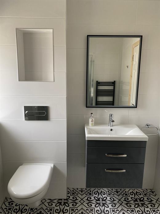 Bathroom with patterned floor tiles and wall-hung toilet