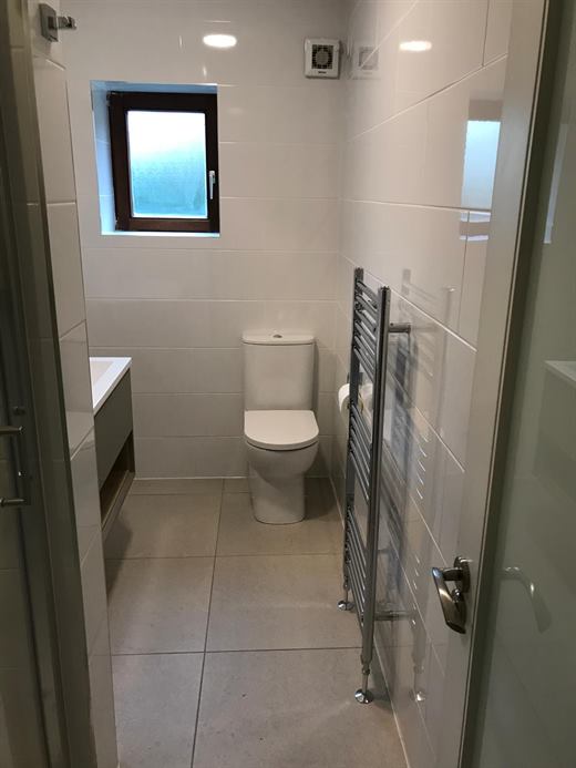 Bathroom with toilet, heated towel rail and large floor tiles
