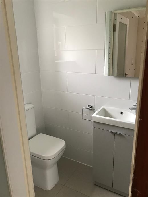 Bathroom with vanity unit and toilet on white tiles