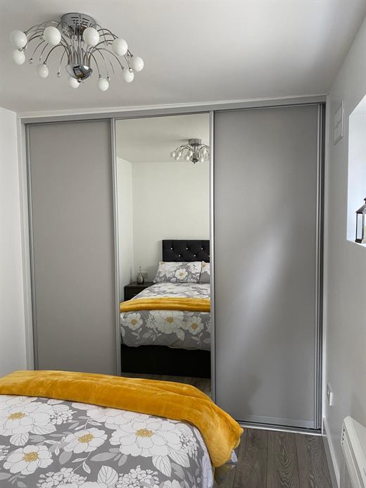 Bedroom with a fitted sliding-door wardrobe and mirrored centre panel