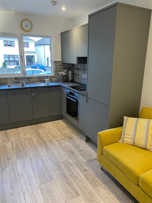 Compact kitchen with grey units and a yellow sofa