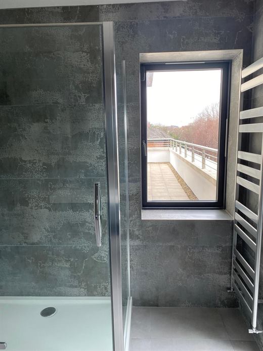 Corner shower enclosure with dark tiles and window
