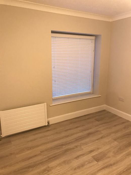 Freshly painted room with laminate flooring and blind