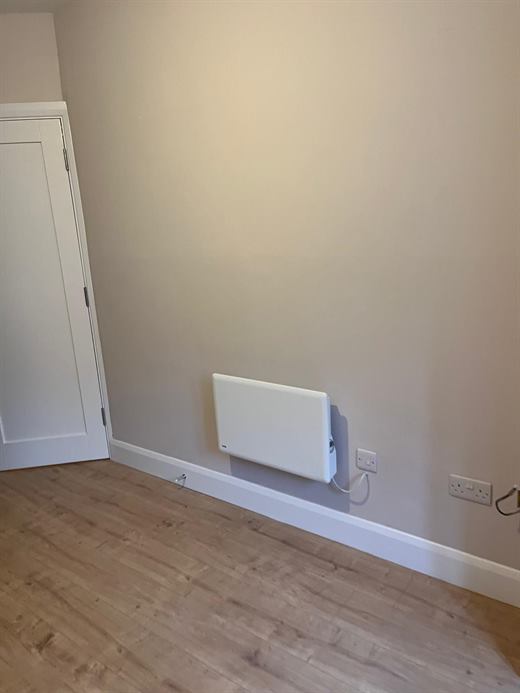 Freshly painted room with wall-mounted radiator and laminate flooring