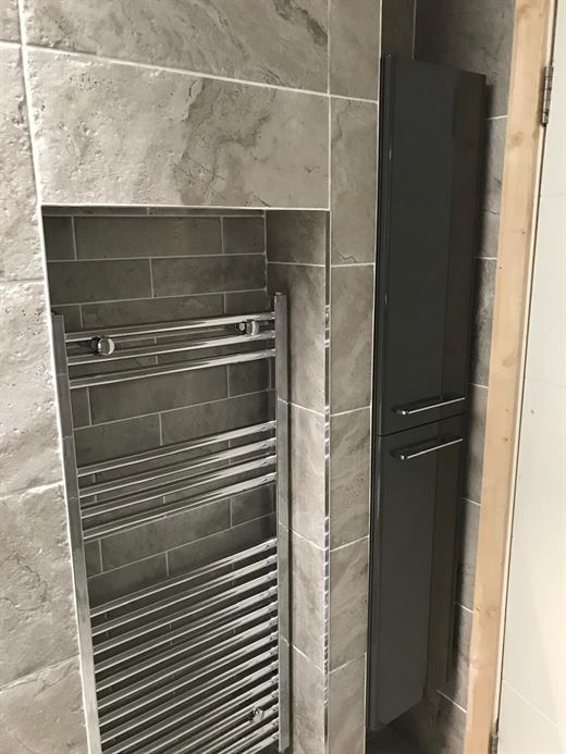 Heated towel rail set into a tiled recess