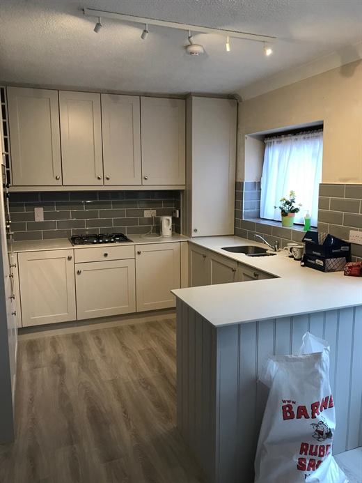 Kitchen with cream shaker units, grey tile splashback and peninsula