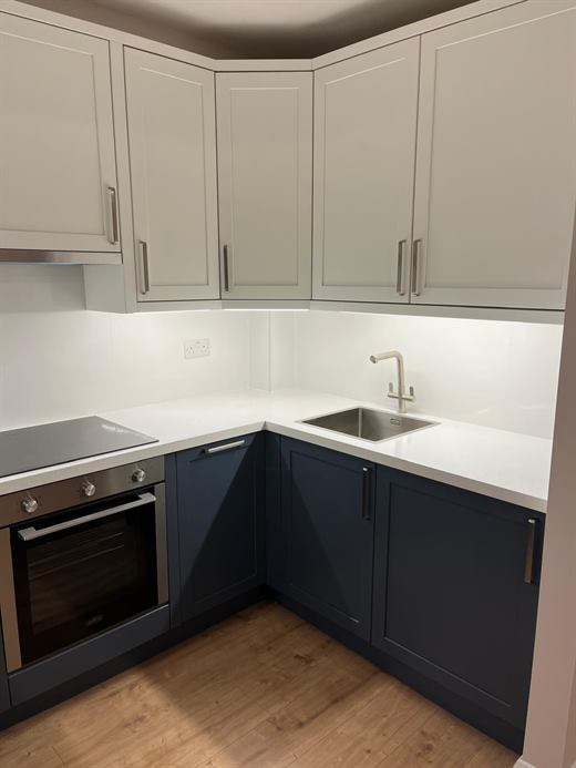 Kitchen with cream wall units, navy base units and white worktop