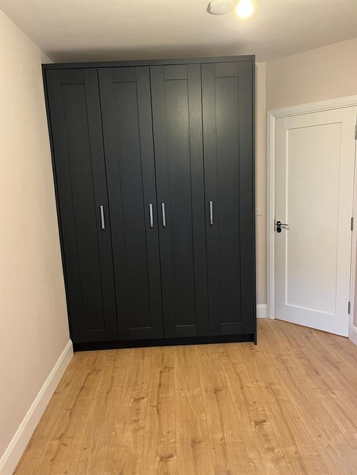 Navy fitted wardrobe with laminate flooring and white door