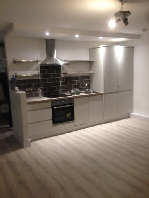 Open-plan kitchen with extractor hood, tiled splashback and laminate flooring