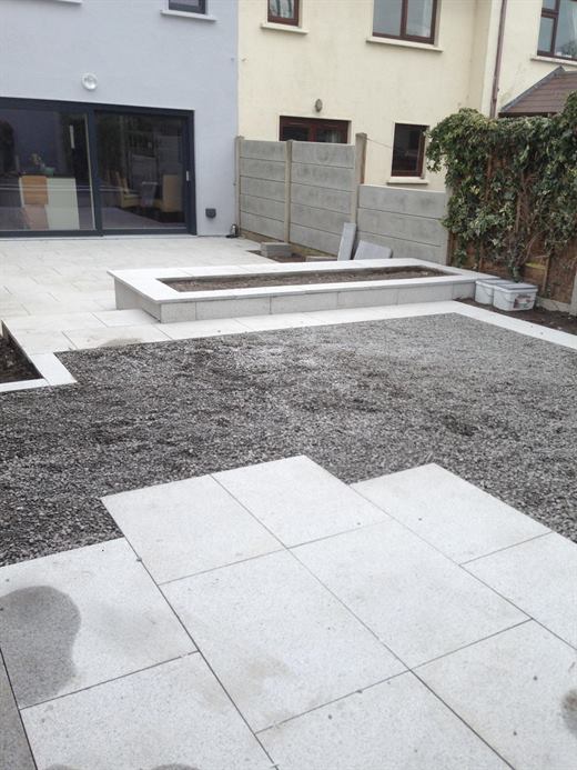 Paved patio and gravel area at the back of a house