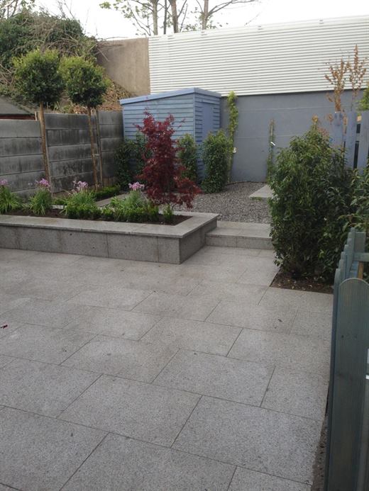 Paved patio garden with raised bed and planting
