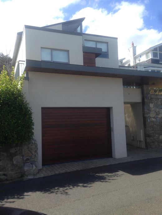 Rendered modern house with a timber garage door and stone boundary wall