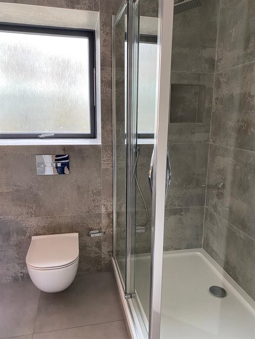 Shower and wall-hung toilet with dark stone-effect tiles