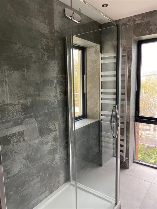 Shower with dark stone-effect tiles and towel radiator
