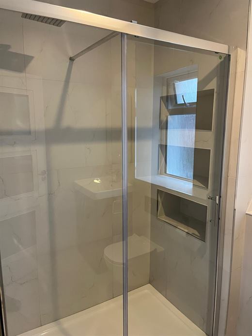Sliding glass shower enclosure with tiled window recess