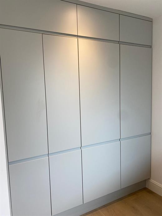 Tall fitted grey cupboards with recessed handles