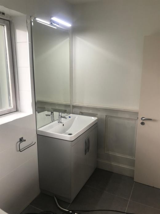 Vanity unit with mirror and light over white tiles
