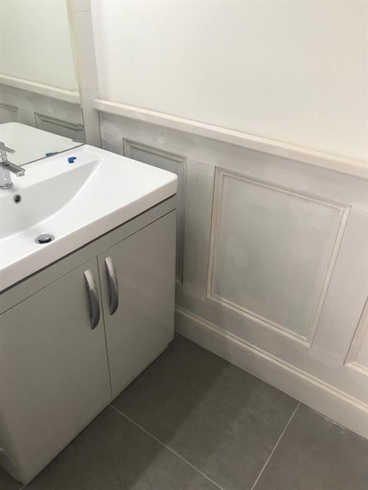 Vanity unit with panelled wall and grey floor tiles