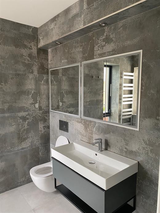 Wide basin on a grey vanity with dark stone-effect tiles